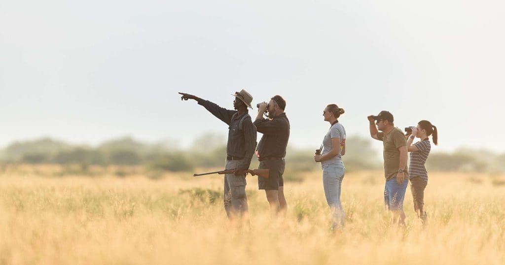 Tour guide and family of four adults sightseeing at a an open location in Botswana.