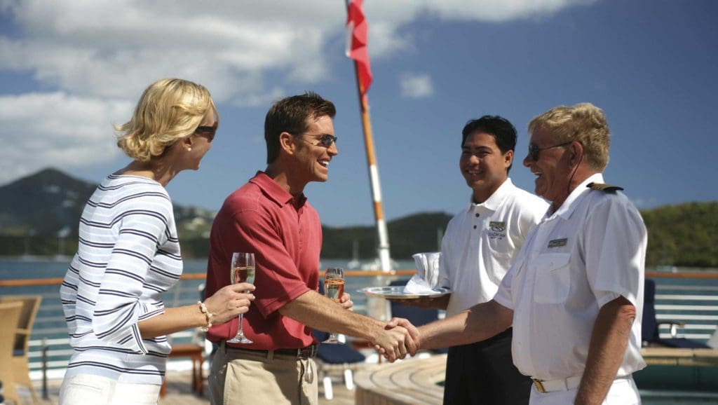 Luxury yacht captain and crew welcoming aboard a couple.