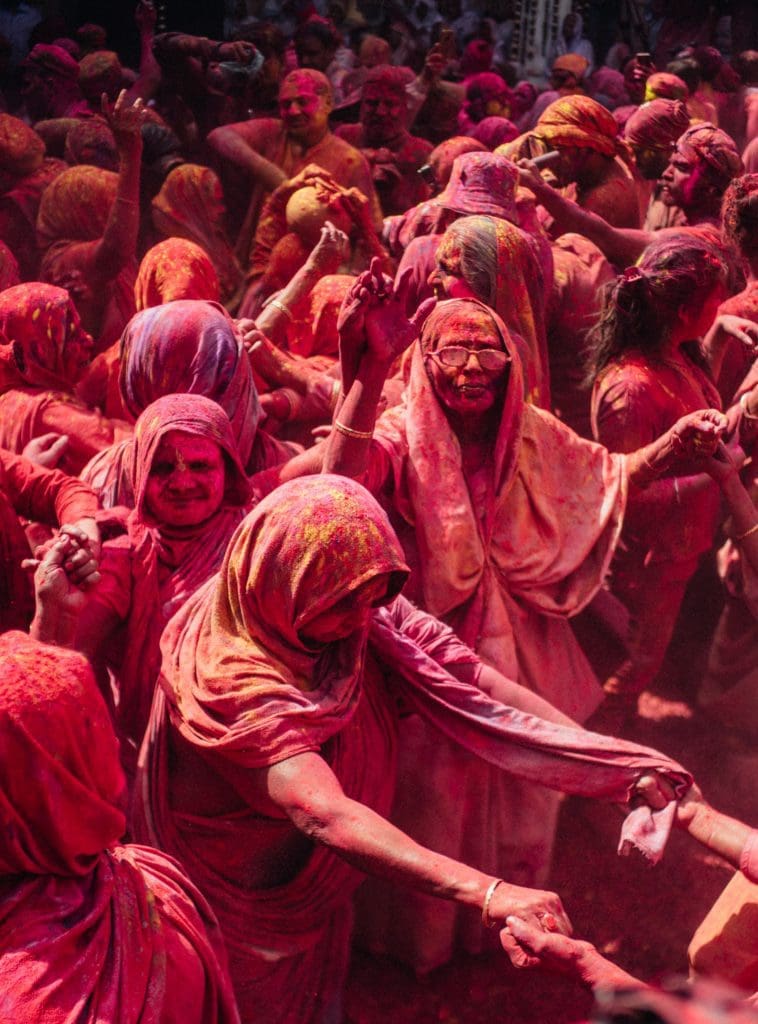 Group of widowed women covered in colored dust in Vrindavan celebrating Holi.