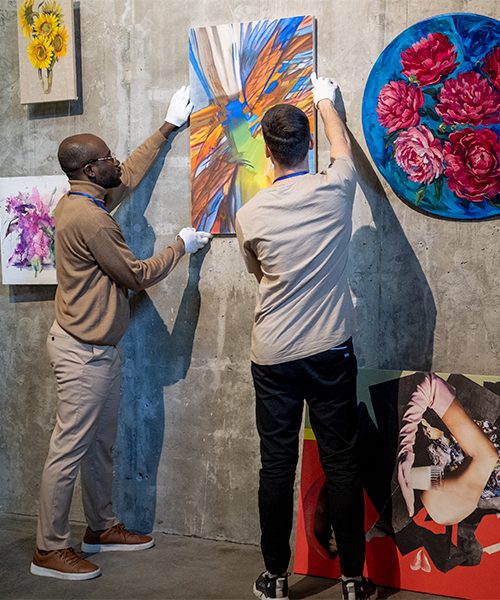 two-young-male-workers-of-art-gallery-hanging-pain-